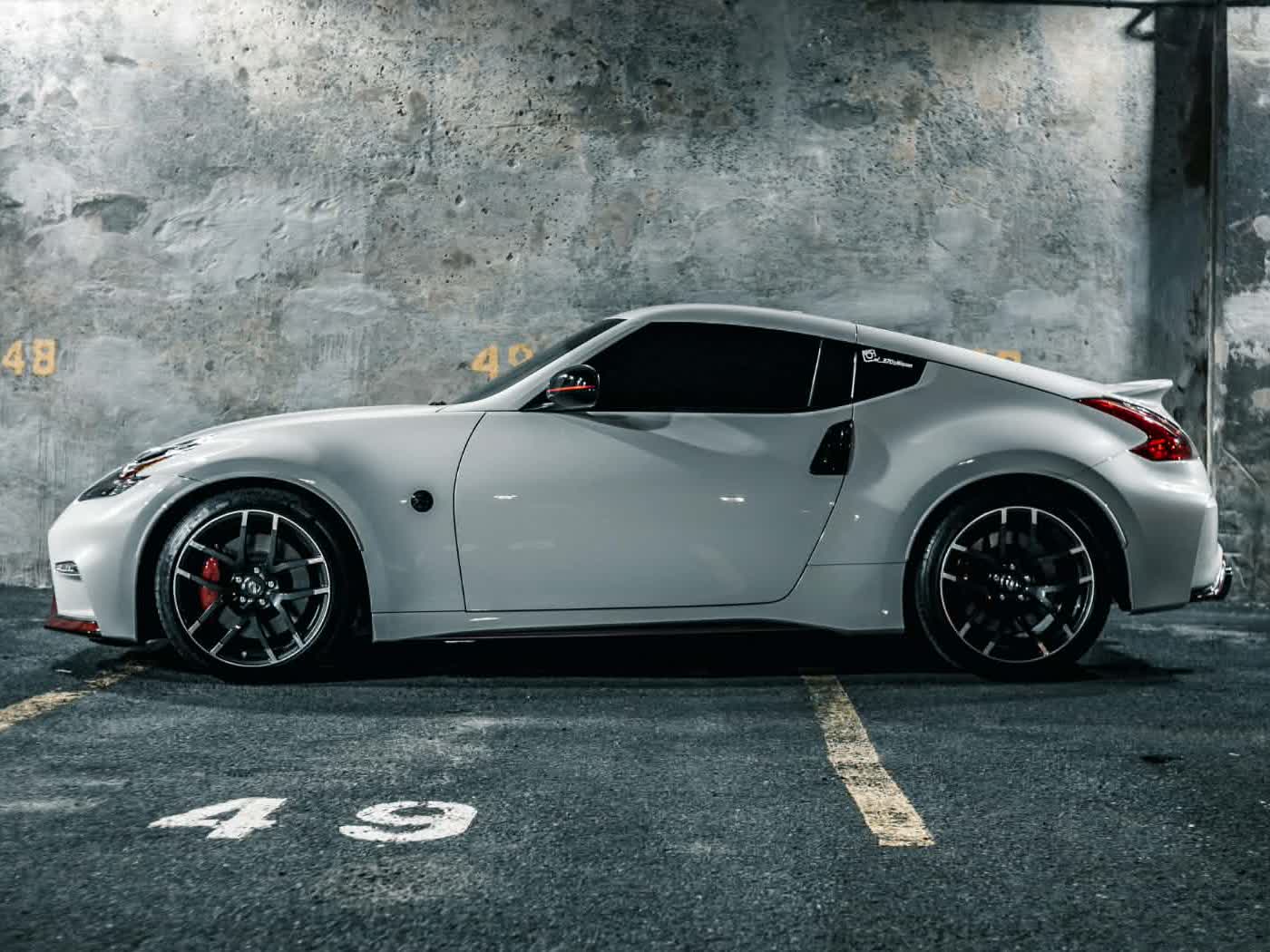 White Nissan 370Z with dark tinted windows in a dramatically lit parking garage